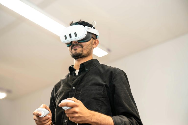 An adult man wearing a VR headset and holding controllers, immersed in gaming indoors.